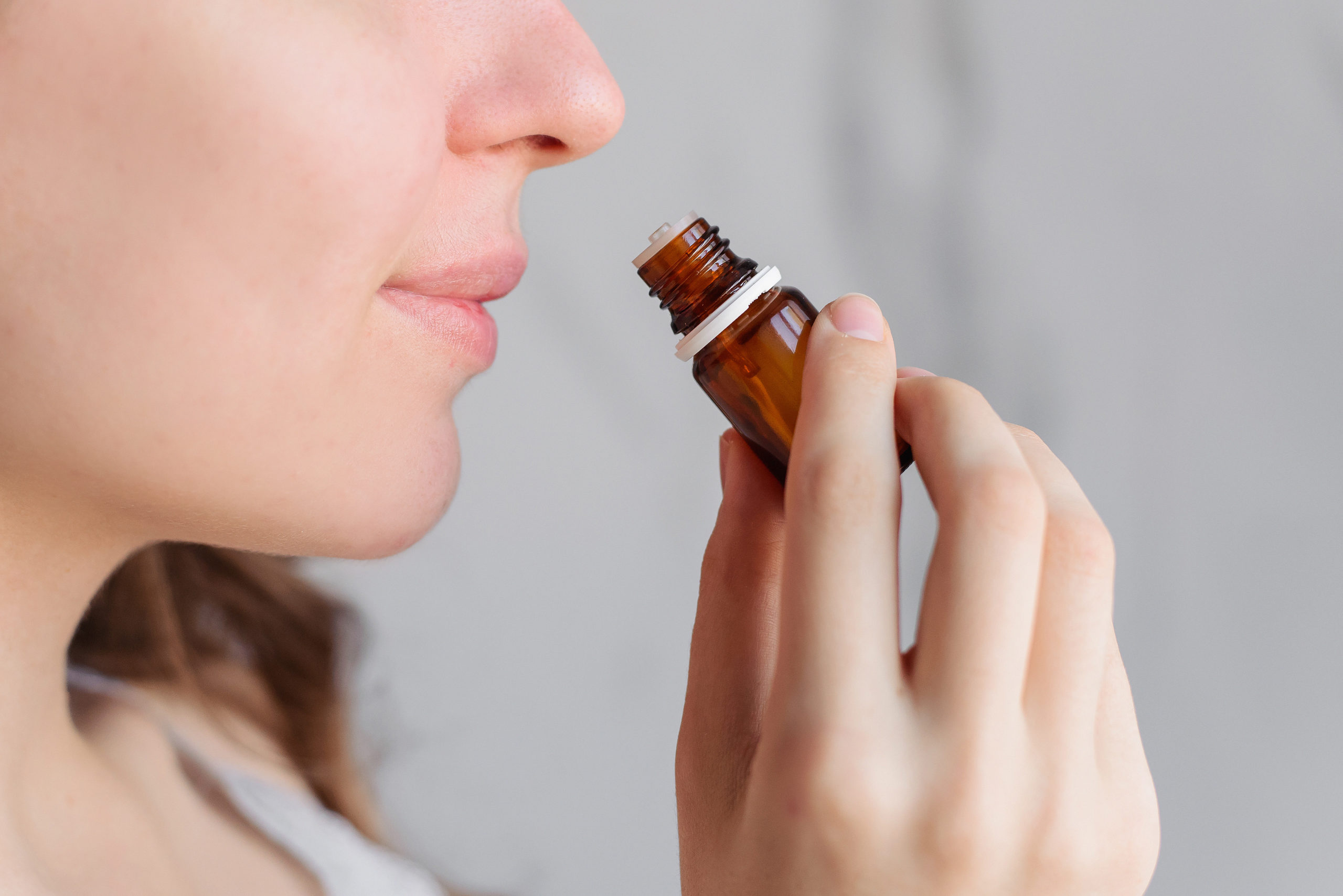 A woman gracefully inhaling the aroma of medicine from a bottle, exploring its scent and potential benefits